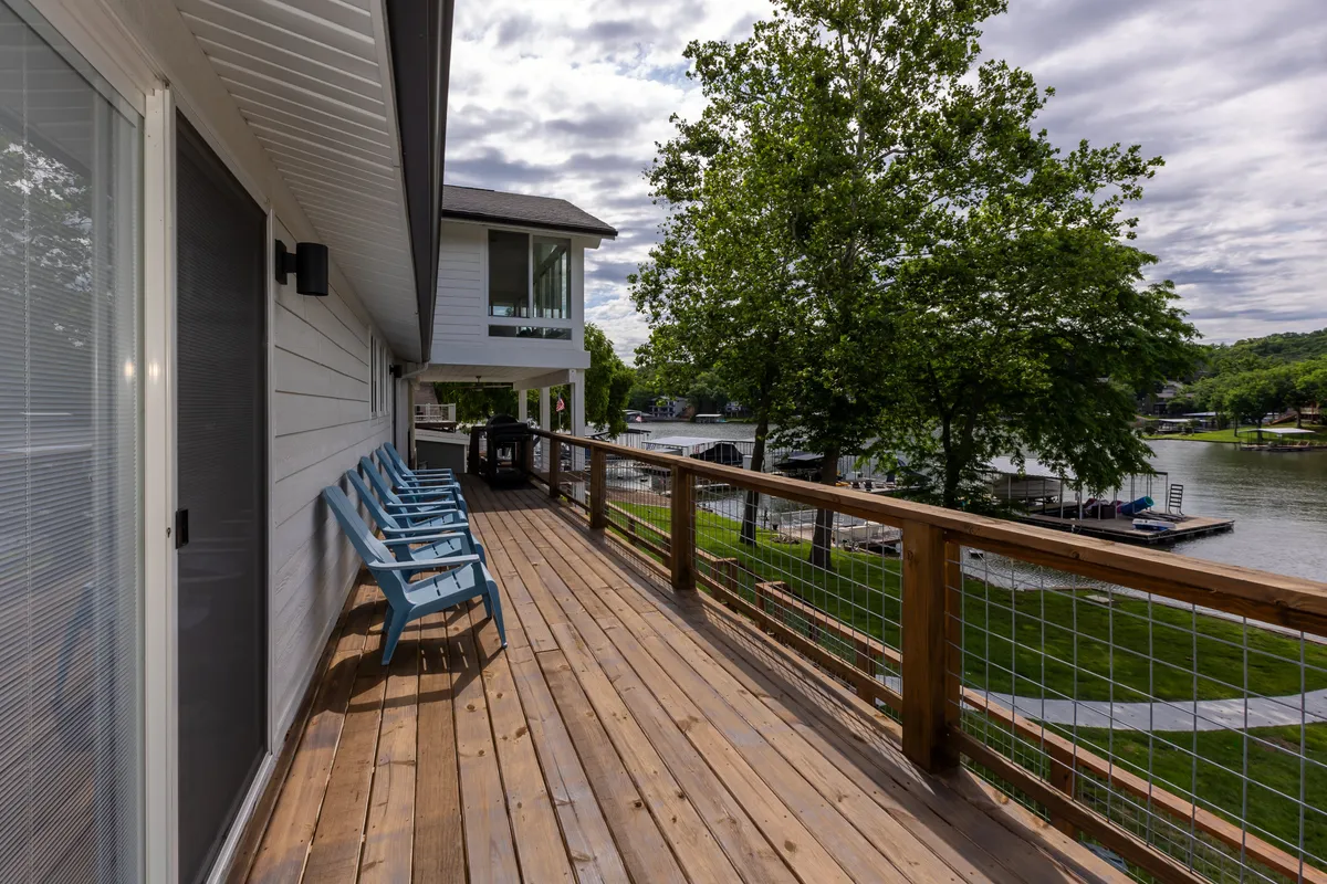 A wide view of the modern house exterior, showing an expansive lawn and an inviting deck area designed for outdoor gatherings. The scene conveys plenty of space for family games, group barbecues, or simply lounging in the sun, all set against the backdrop of nature.