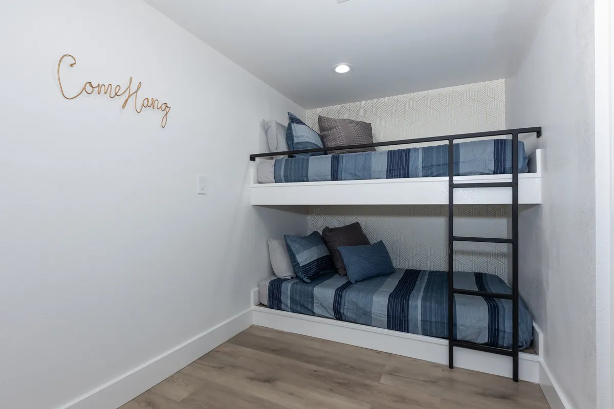 A cozy interior with bunk beds and playful decorative wall text, suggesting a family-friendly bedroom perfect for children or group stays. The room is inviting and designed with vacation memories in mind.